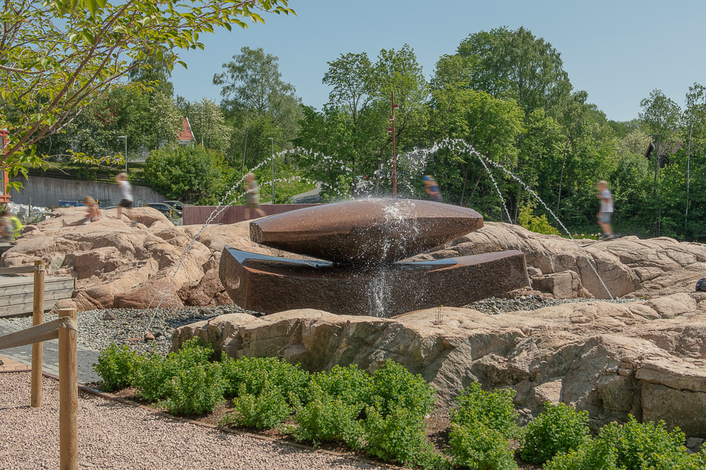 Bilde av fontene med to slipte stener som ligger oppå hverandre, i et parkområde i Heggedal.