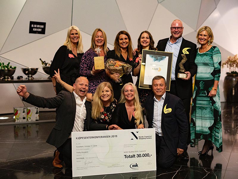Bildet viser 10 glade personer som jobber for AMFI Madla. De er glade og fornøyde og holder i en sjekk de vant for årets største kjøpesenter i 2019.