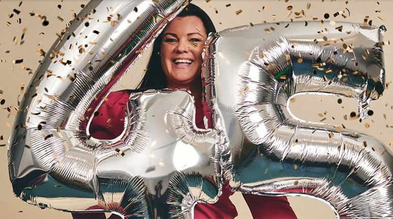 en kvinne som holder ballonger med tallet 45