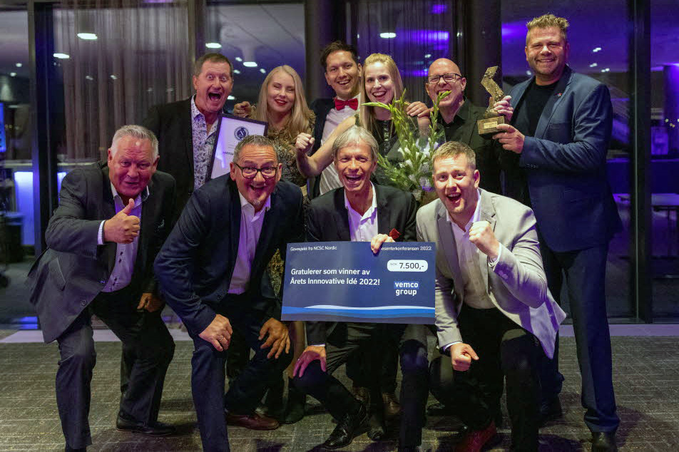 Gruppe med ansatte på kjøpesenter holder pokal og premiesjekk. Foto.